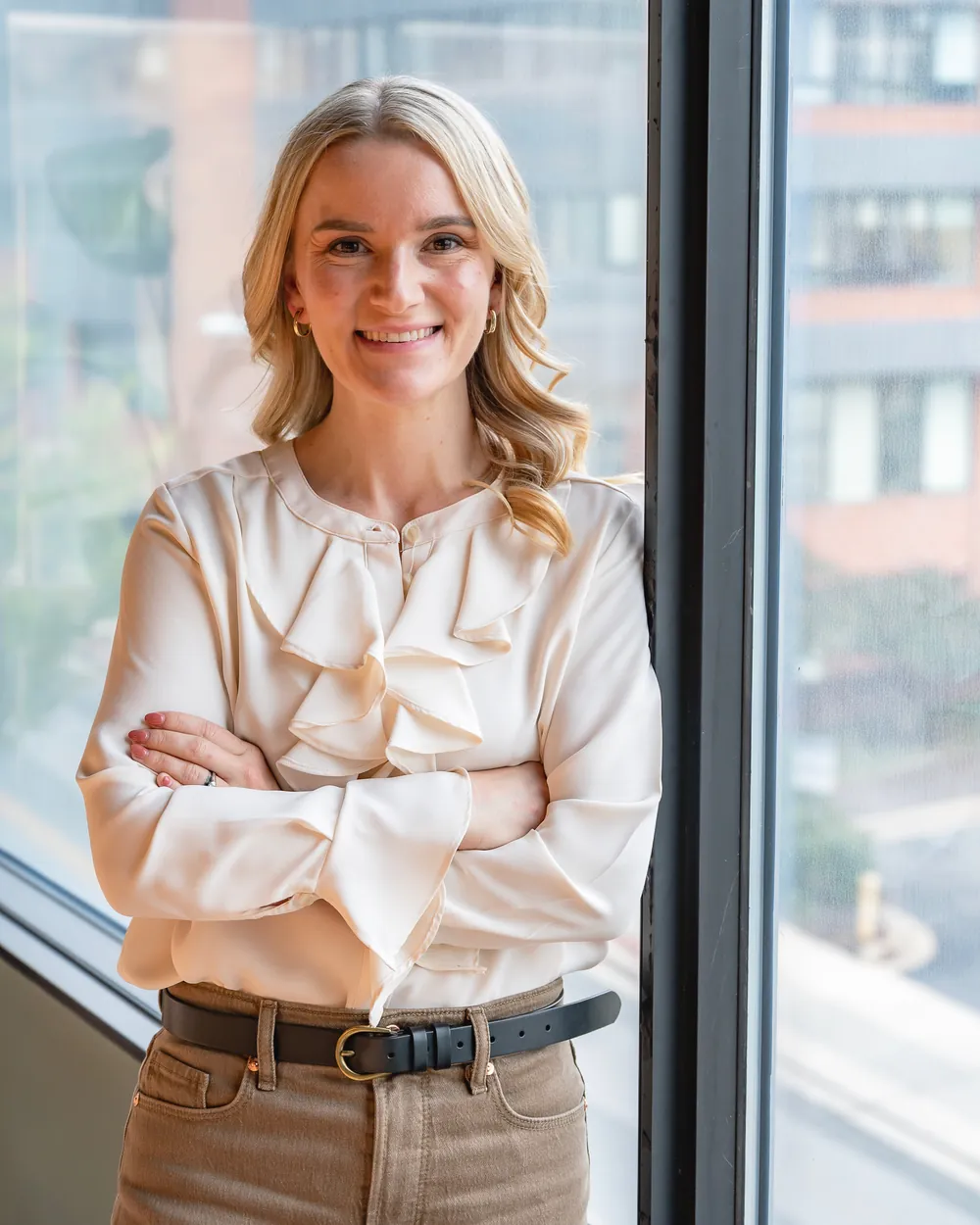 Dr. Kate standing with arms crossed beside an office window, smiling